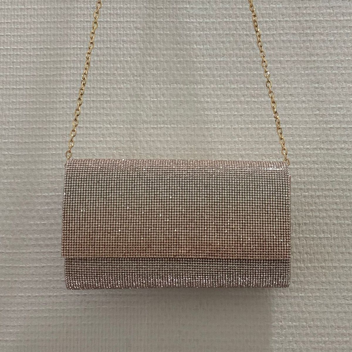 Lange enveloptas in abrikooskleur met heldere kristallen, hangend aan de ketting