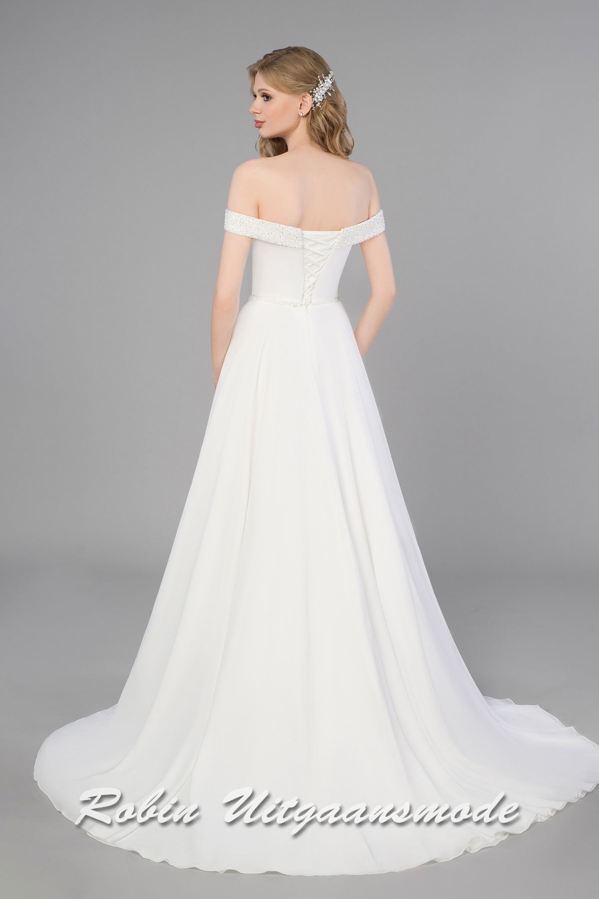 Achterpand van de Trouwjurk met glitter off-shoulder halslijn, aansluitend lijfje met vetersluiting en A-lijn rok met split
