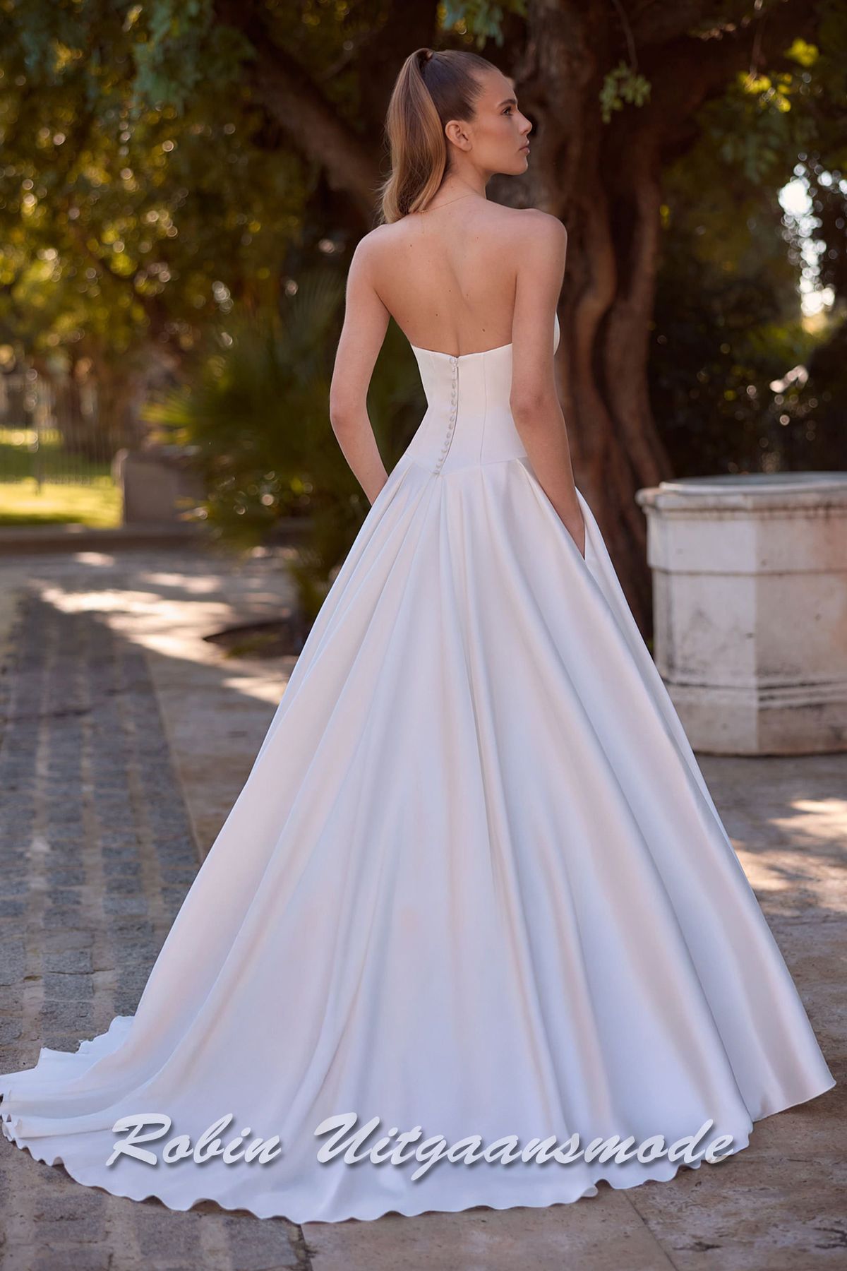 Achterkant van de Strapless trouwjurk met lage taille, een A-lijn rok met verborgen zakken en kathedraal sleep