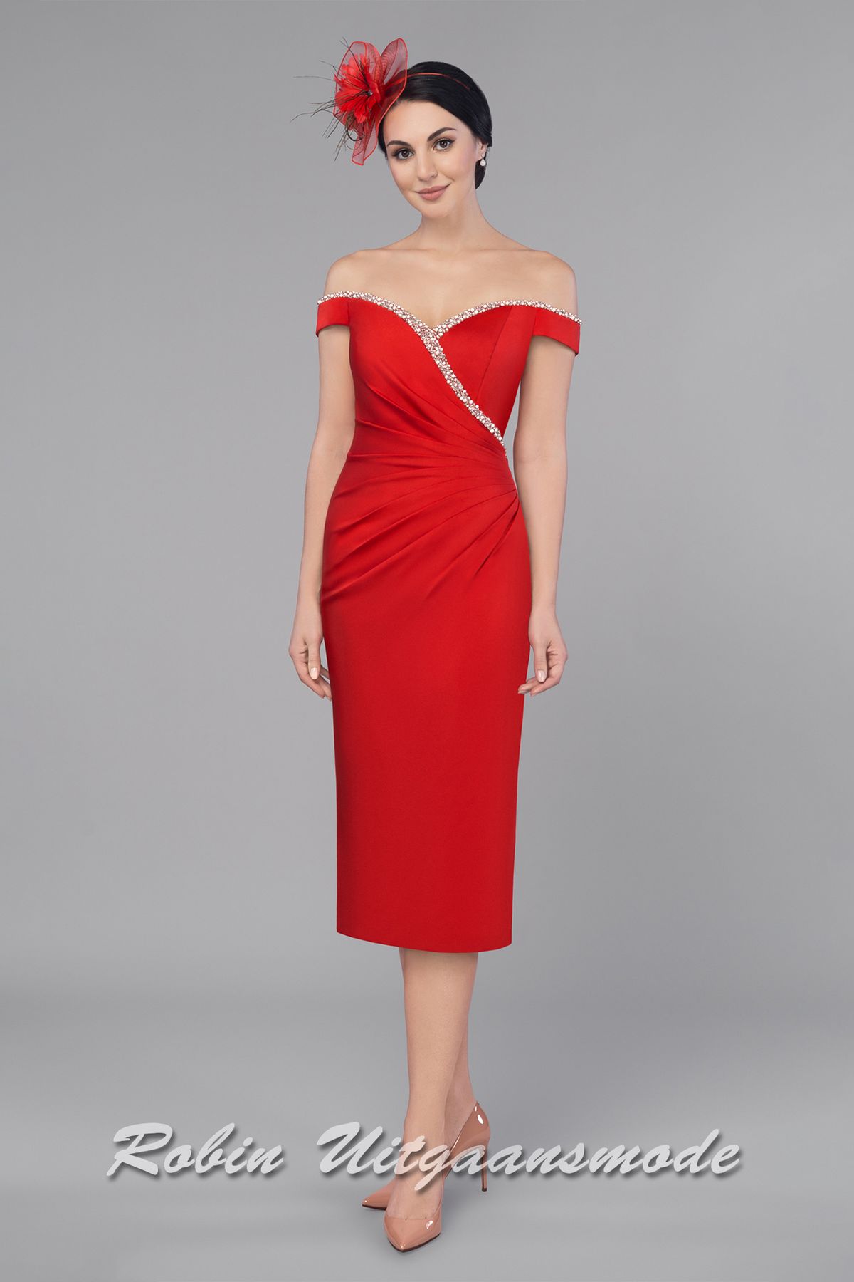 Een glamoureus en charmante indruk maak je in dit off-shoulder avondjurkje. De heartshape halslijn is afgezet met een band van glinsterende steentjes, welke wegloopt in de taille en doorloopt over de afhangende mouwen. De rechte rok valt tot over de knie en geeft voldoende ruimte om vrij te bewegen.
