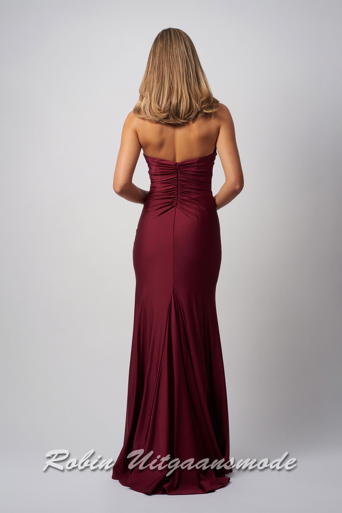 Achterkant van de Bordeauxrode strapless galajurk met hoge split, een klein sleepje en een heartshape bustelijn