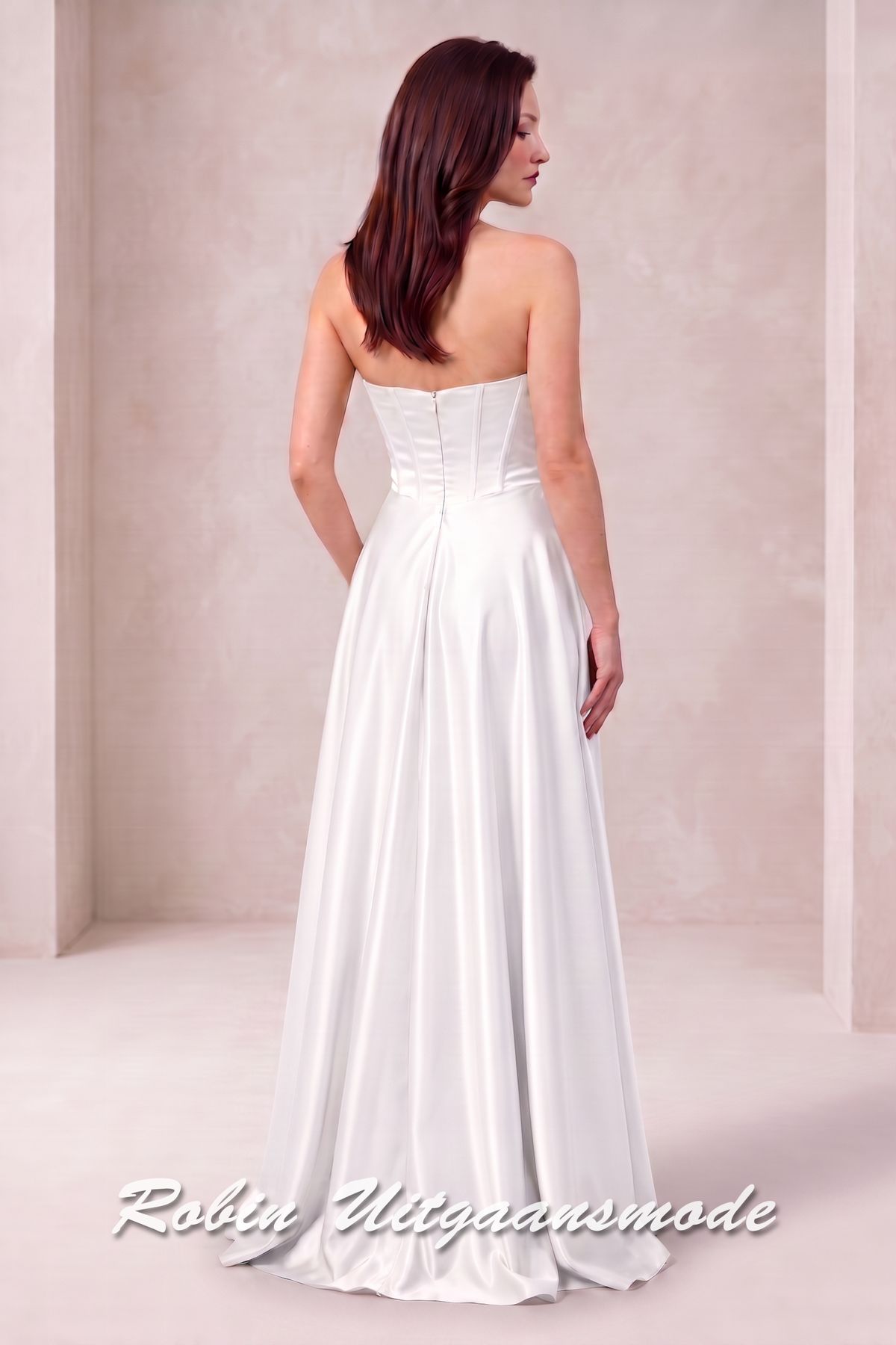 Achterkant van de Trouwjurk met strapless asymmetrische halslijn, brede banden schuin over de buste lopend naar de linkertaille en licht geplooide rok tot op de grond