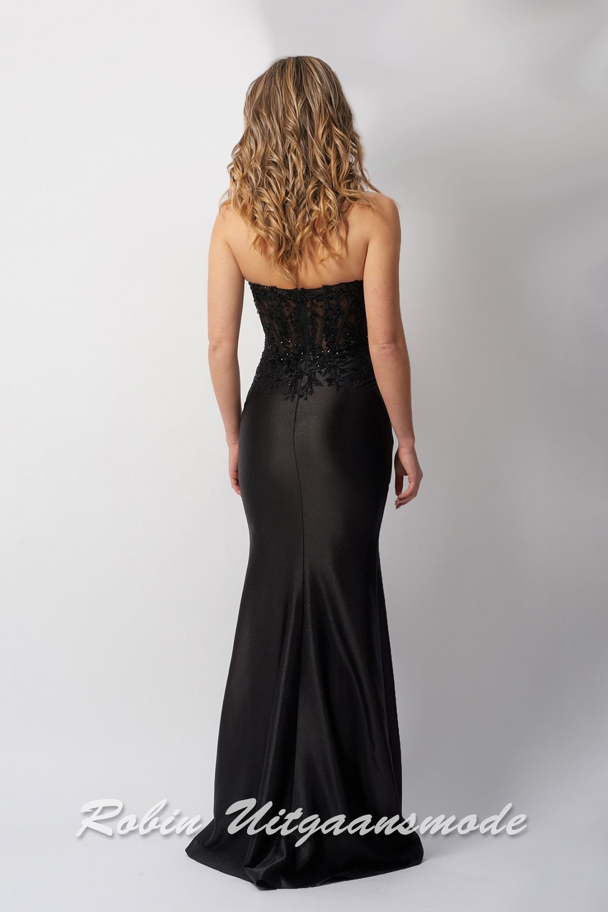 Achterkant van de Strapless zwarte avondjurk met heartshaped kanten top, versierd met kralen en licht geplooide chiffon rok tot op de grond.