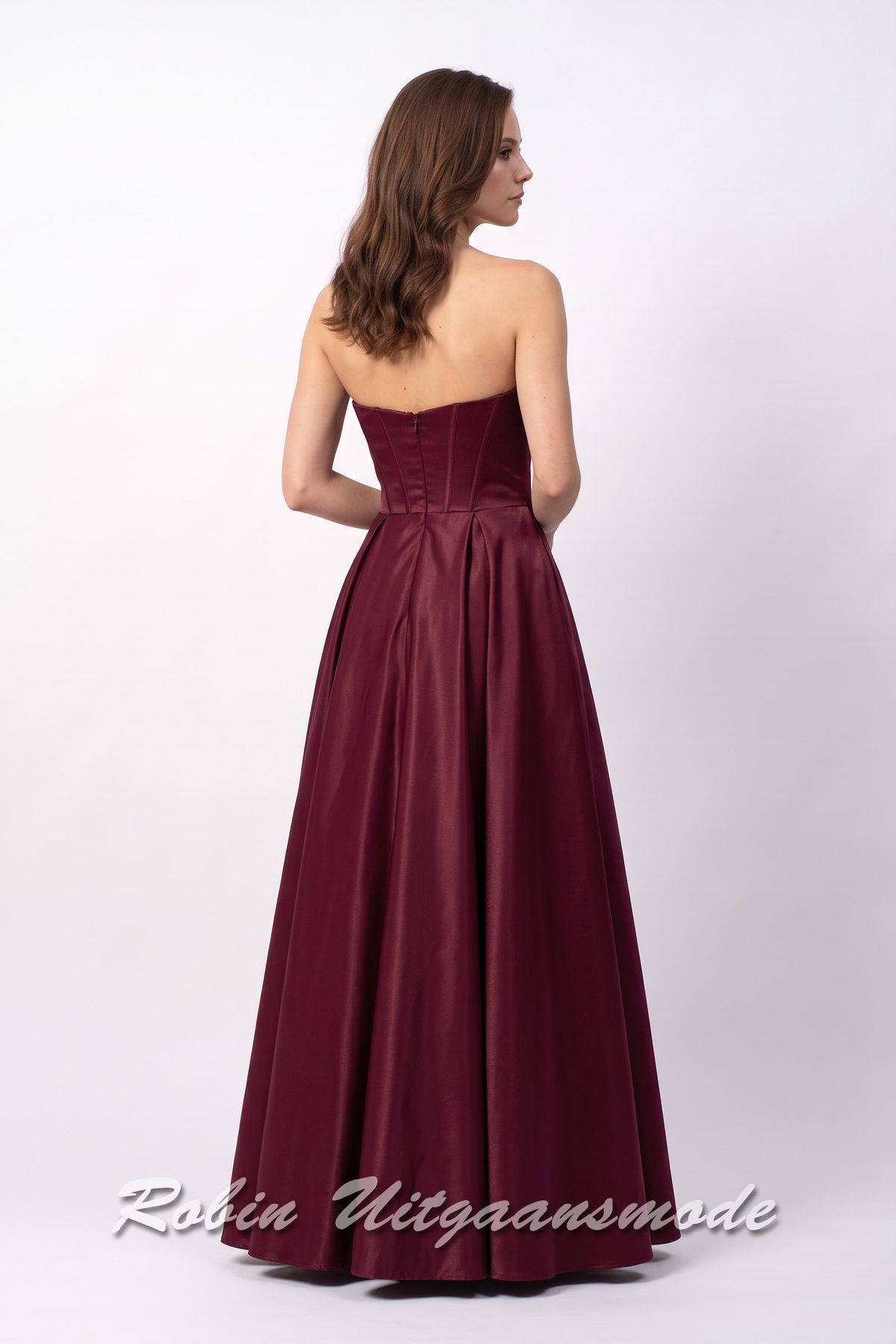 Achterkant van de Strapless berry rode avondjurk met A-lijn rok, een heartshape bustelijn versierd met sprankelende pailletten en afgewerkt met waterval band