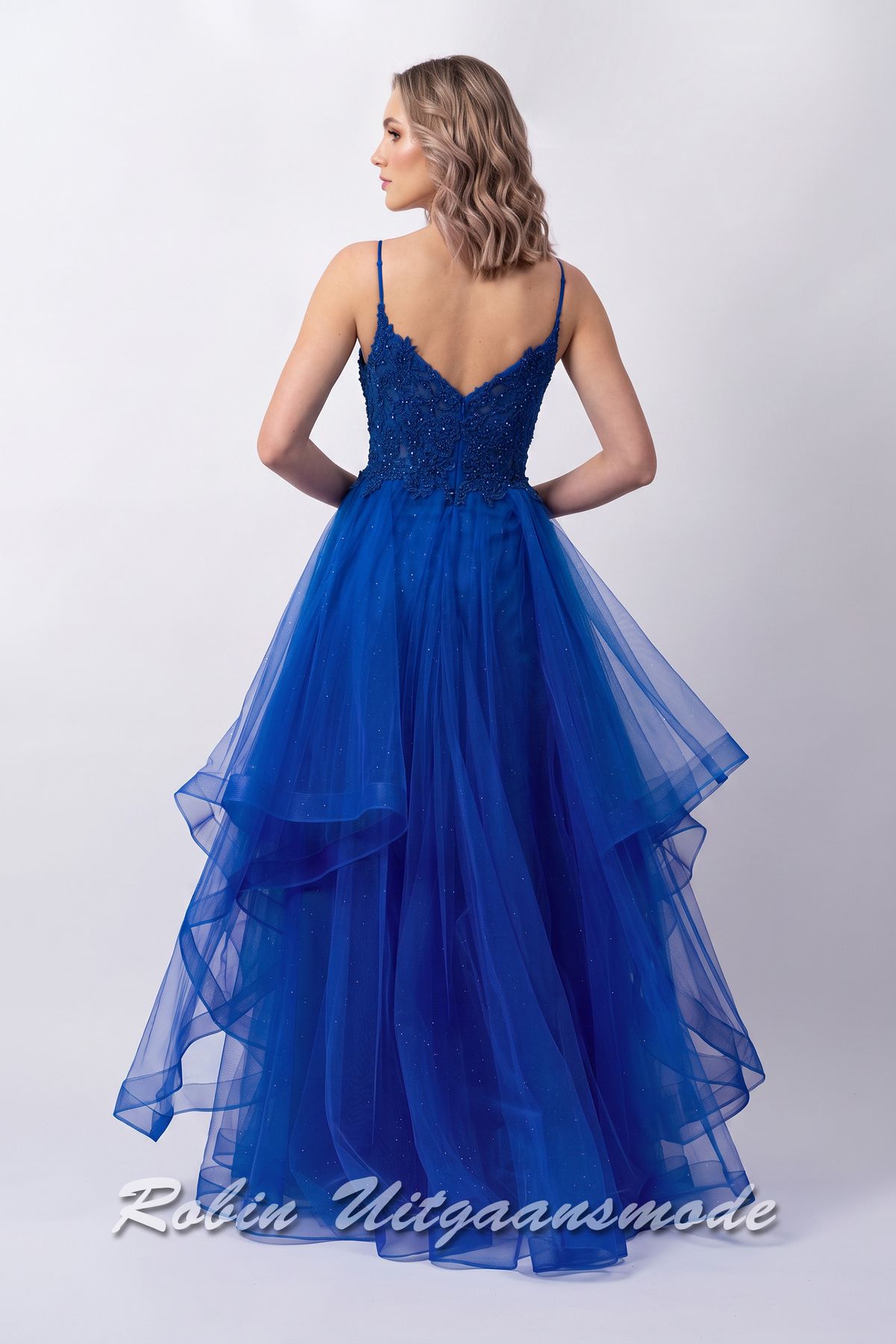 Achterkant van de Royalblauwe galajurk met kanten lijfje, smalle bandjes, en een speelse rok met asymmetrische soft tule lagen