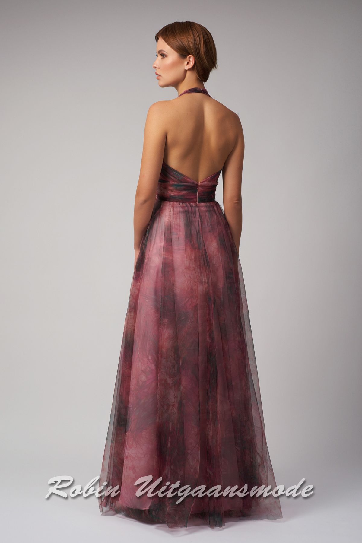 Achterkant van de Berry halter avondjurk met print, een vrouwelijk V-halslijn, brede taille band en iets wijd uitlopende rok met tule toplaag