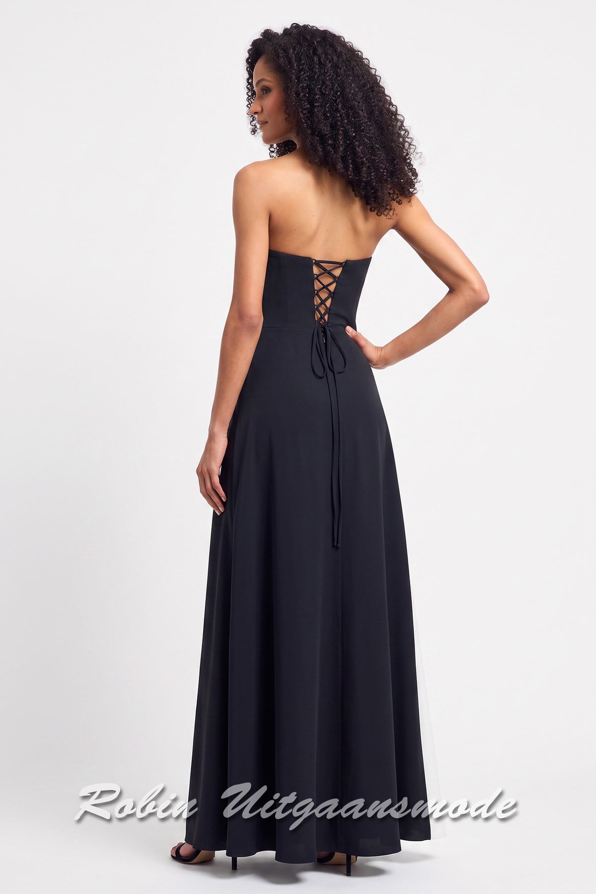Achterkant van de Zwarte avondjurk met asymmetrische witte baan over de rok en een strapless top met spits toelopende uiteinde aan de linkerzijde