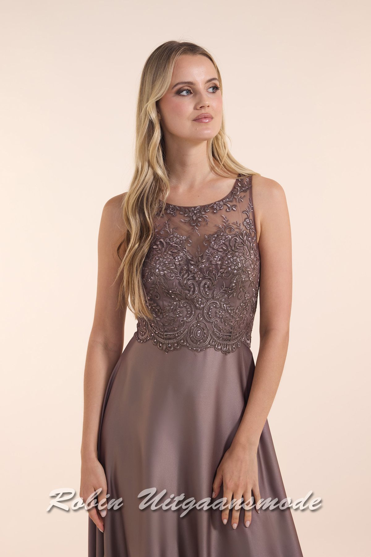Close-up van de Hooggesloten mokkabruine avondjurk met kanten lijfje, boothals lijn en een licht geplooide satijnen rok