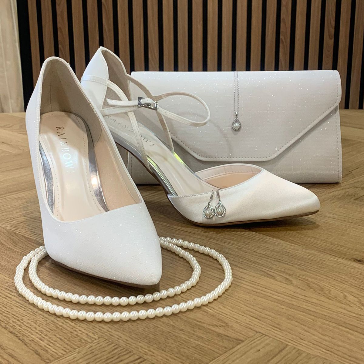 Ivoorkleurige accessoires om je bruidslook mee af te stijlen, bruidsschoenen, parel ketting en bruidstasje