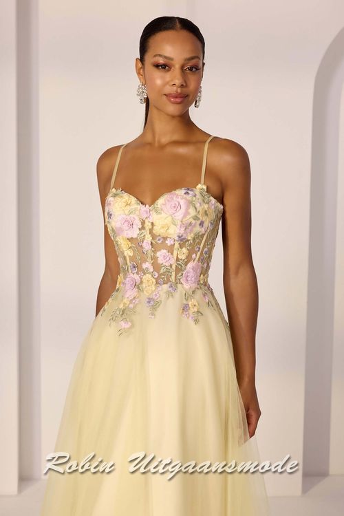 Close-up van de Gele A-lijn galajurk met geborduurde bloemen in het roze, lila en geel op de korset top, een heartshape bustelijn en wijduitlopende rok met tule toplaag.