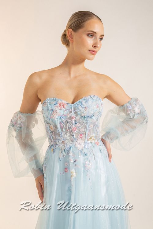 Close-up van de Strapless lichtblauwe galajurk met bloemen lijfje, losse pofmouwen van tule en springerige rok van soft tule