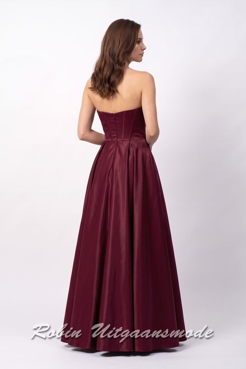 Achterkant van de Strapless berry rode avondjurk met A-lijn rok, een heartshape bustelijn versierd met sprankelende pailletten en afgewerkt met waterval band