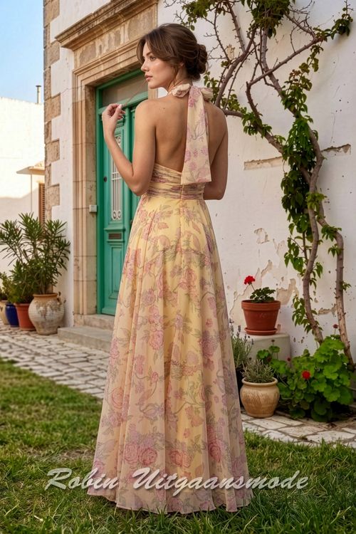 Achterkant van de Citroengele avondjurk met fleurige rozen print, een haltersluiting met strik en een wijd uitlopende chiffon