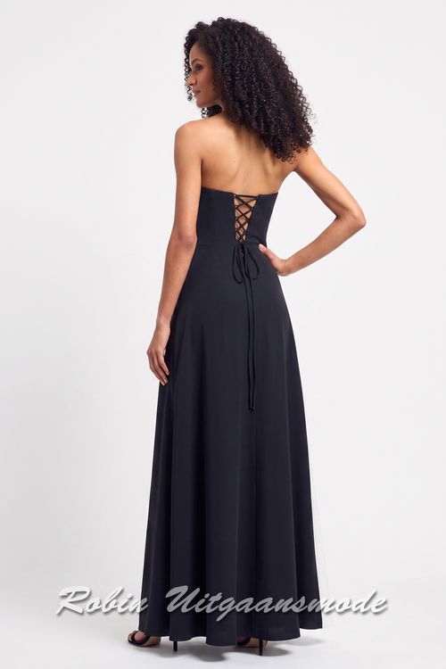 Achterkant van de Zwarte avondjurk met asymmetrische witte baan over de rok en een strapless top met spits toelopende uiteinde aan de linkerzijde