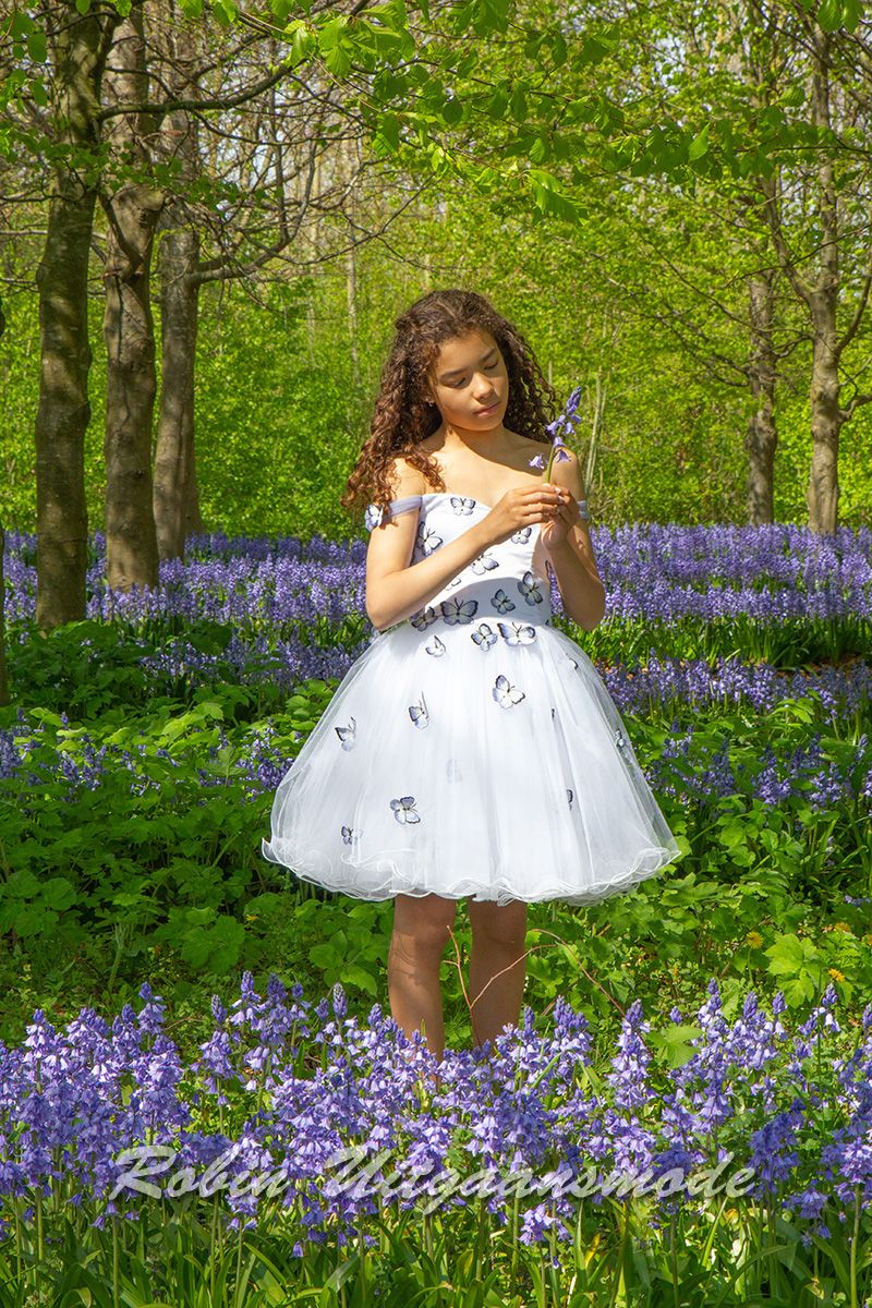 Feestelijke jurkje van vrolijke vlinderstof, met strapless lijfje, afhangende schouders en wijde tule rok, in een bloemenveld