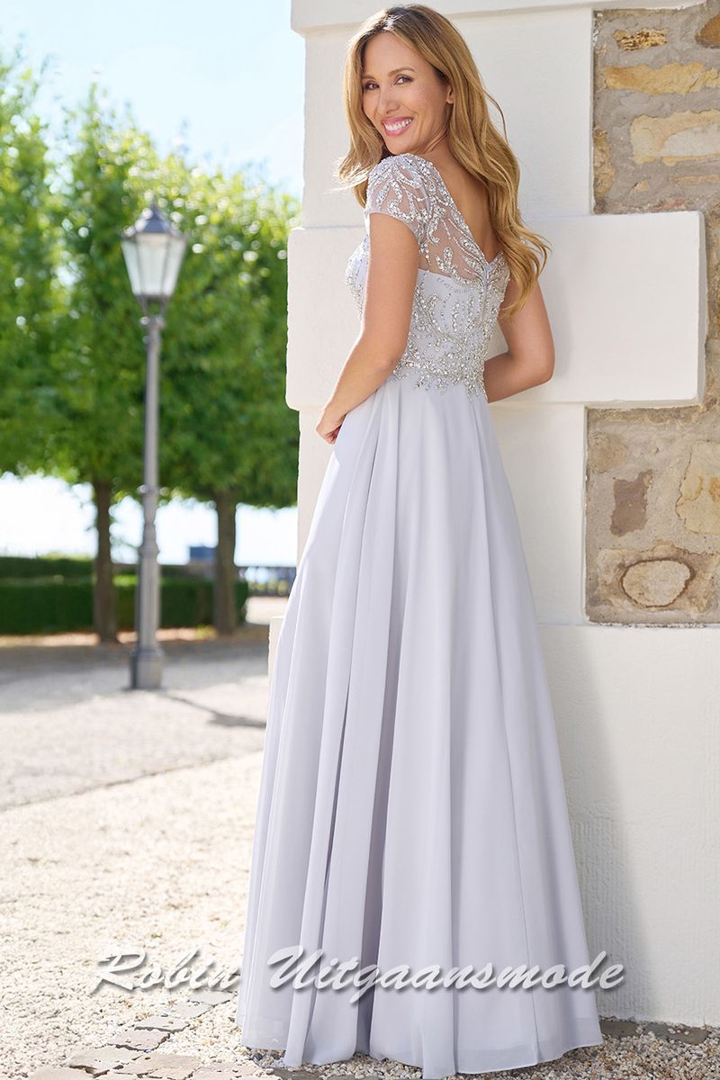 Achterkant van de Zilvergrijze  lange avondjurk met kanten lijfje versierd met sprankelende steentjes, kapmouwtjes en chiffon rok met split